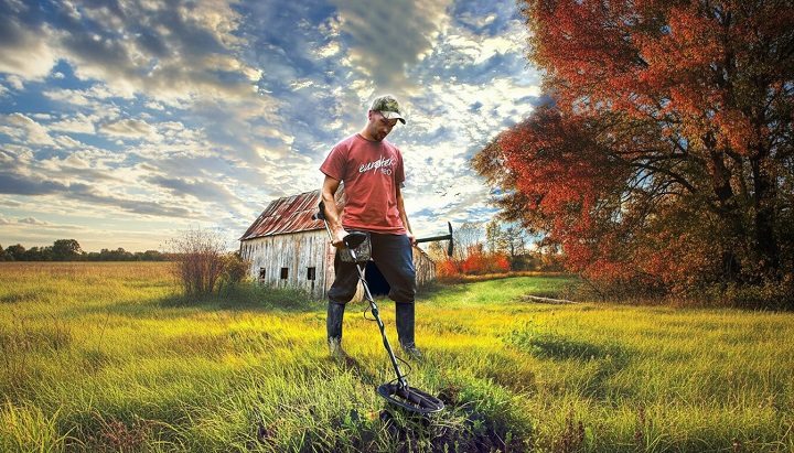 Utilisateur balayant un champ avec le détecteur de métaux Teknetics Eurotek Pro.