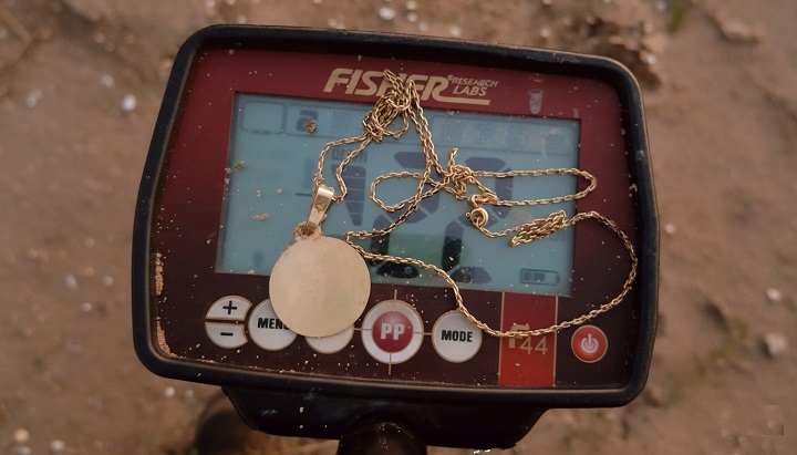 prospecteur ayant trouvé un chaine en or avec son détecteur Fisher