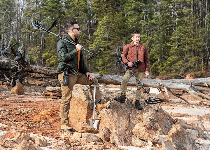 un père et son fils se préparant à détecter au bord d'une foret avec des enrochements