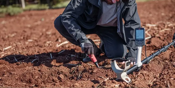 Minelab X-Terra Elite 5 Prospecteur utilisant un pointeur de localisation à côté du détecteur Minelab X-Terra Elite dans un champ labouré
