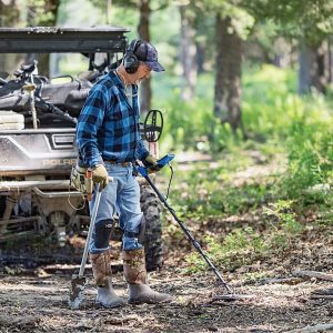 Utilisateur en pleine prospection en forêt avec le détecteur de métaux multifréquence Garrett Vortex VX7 et son casque sans fil.
