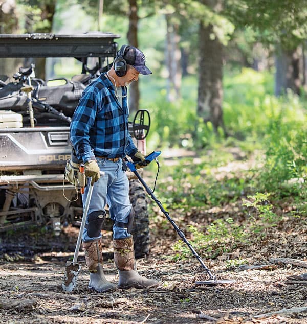 Garrett Vortex VX7 4 Utilisateur en pleine prospection en forêt avec le détecteur de métaux multifréquence Garrett Vortex VX7 et son casque sans fil.