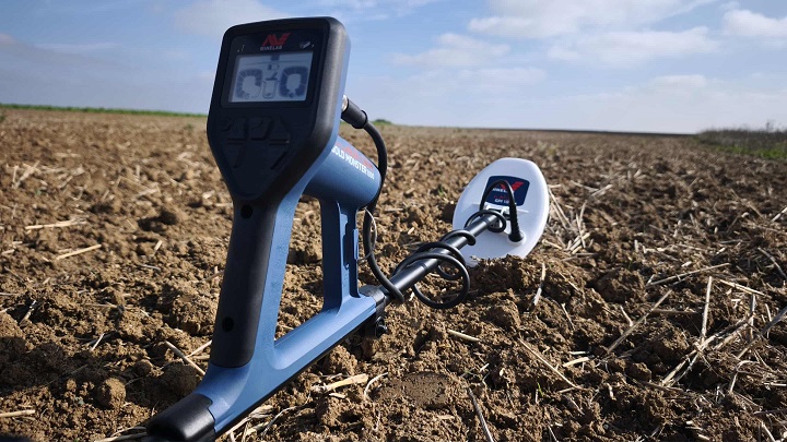 Minelab Gold Monster 1000 : Test et avis sur le terrain 9 Détecteur Minelab Gold Monster 1000 avec boîtier et disque de détection posé dans un champ labouré