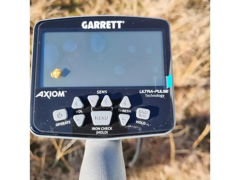 Garrett Axiom : Test et avis sur le terrain 2 Gros plan sur le boîtier de contrôle du Garrett Axiom avec une pépite d'or posée sur l'écran