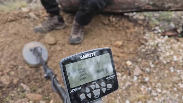 Garrett Axiom : Test et avis sur le terrain 3 Écran de contrôle et disque du détecteur d'or Garrett Axiom posé au sol lors d'une session de prospection