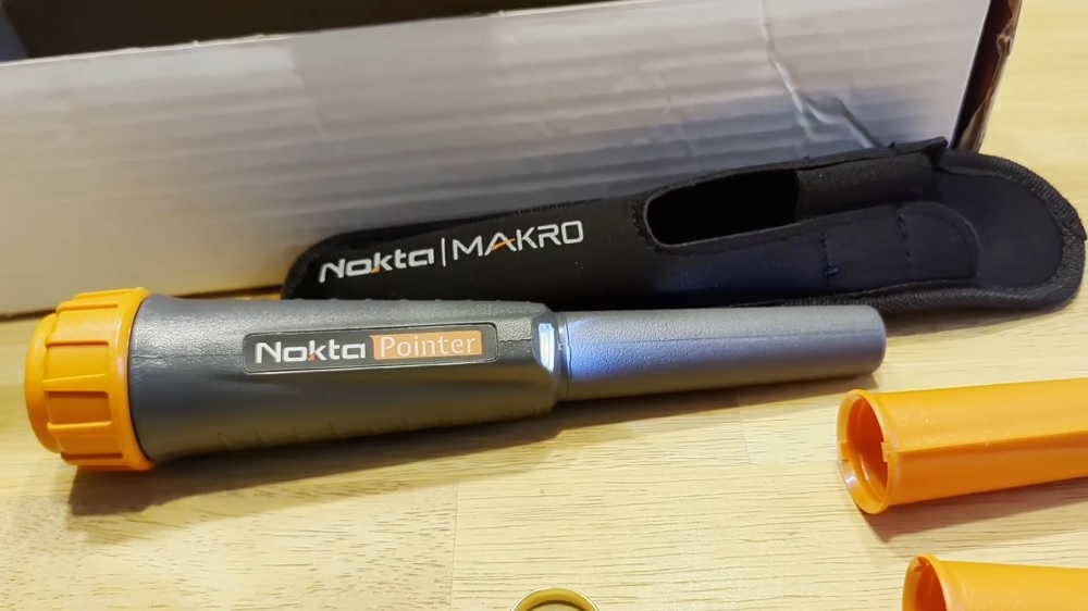 Nokta Pointer : Test et avis terrain sur ce pinpointer 18 kHz 1 Gros plan sur le corps du pinpointer Nokta Pointer posé à côté de son étui et de ses coques d'usure