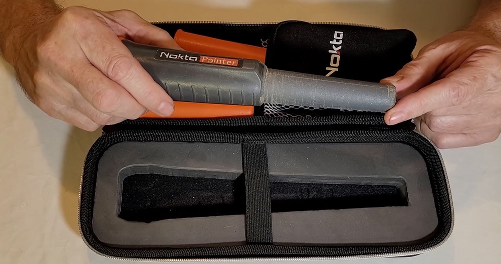 Prise en main de la sonde Nokta Pointer au-dessus de sa mallette rigide de protection avec mousse